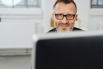 Businessman smiling over his desktop monitor