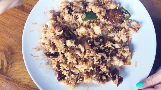 Woman eating steam rice with beaf in a black pepper sauce. Bali island, Asia.