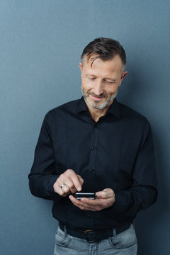 Smiling man typing a text message on a phone