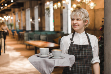 A friendly waitress distributes coffee drinks to customers in a cafe