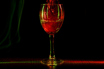 A goblet in night club. Restless wine in a glass. The light effect.