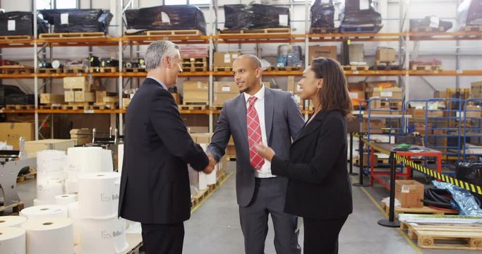 4K Business group meet and shake hands in large storage warehouse. Slow motion.
