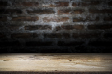 Wood table top on old dark brick wall background.