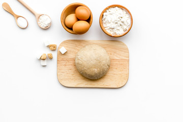 Ball of fresh raw dough near ingedients and cookware on white background top view copy space