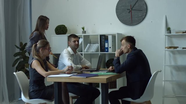 Furious female boss scolding her team for bad work results during the meeting in office. Ineffective office workers sitting at table and listening to irritated boss yelling with annoyed expressions