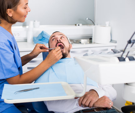 Dentist female in uniform is examinating of male in dental clinic