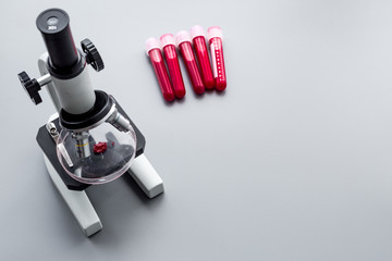 Do blood test in laboratory. Analysis. Blood samples in test tubes near microscope on grey background top view copy space