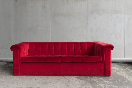 Rotes Sofa vor Betonwand