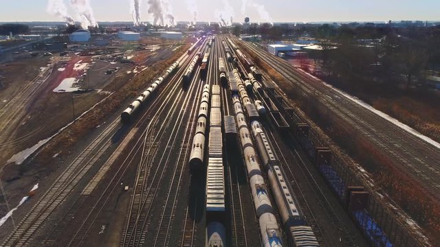 Looking down on industrial railroad train yard, many trains, tracks. Dynamic aerial view.
