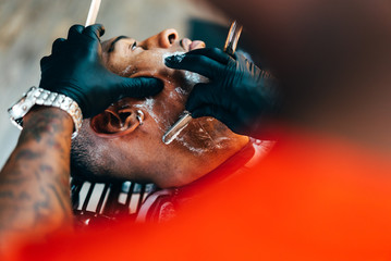 Barber shaving beard of customer