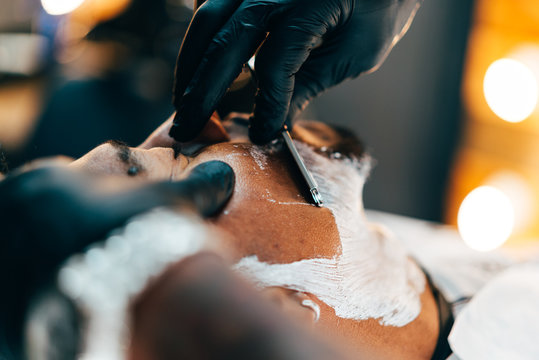 Barber shaving beard of customer
