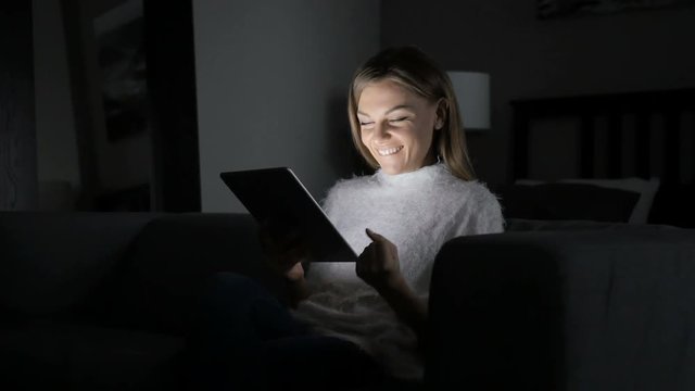 Woman Reacting to Success while Using Tablet at Night