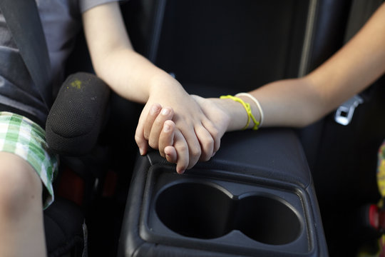 Children holding hands in car