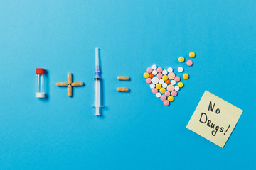 Pills bottle plus syringe needle equals medication colorful round tablets in form of heart isolated on blue background. Paper sticker sheet text No drugs. Concept of treatment choice healthy lifestyle
