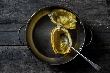 acorn squash in dark moody pan with wood backdrop