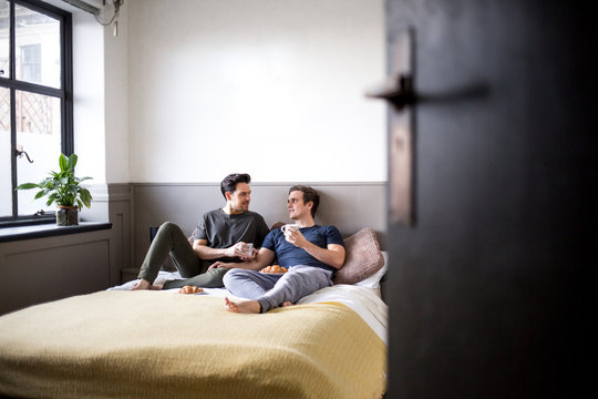 Young male couple relaxing with breakfast in bed