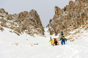 Extreme skiers climb to the top along the couloir between the rocks before the descent of the freeride backcountry