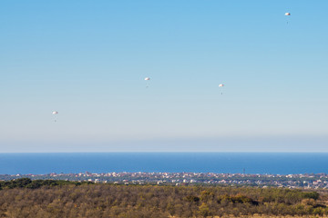 Airborne troops a mass parachute drop over the sea. On a blue sky background.