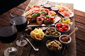 Italian antipasti wine snacks set. Cheese variety, Mediterranean olives, pickles, Prosciutto di Parma, tomatoes, artichokes and wine in glasses