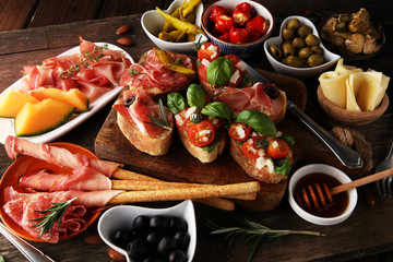 Italian antipasti wine snacks set. Cheese variety, Mediterranean olives, pickles, Prosciutto di Parma, tomatoes, artichokes and wine in glasses