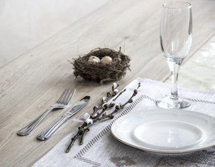 on the table a napkin with a plate of a glass fork and a branch of a willow's nest with quail eggs 