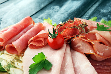 Food tray with delicious salami, pieces of sliced ham, sausage, tomatoes, salad and vegetable - Meat platter with selection