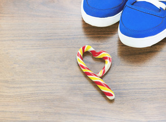 Blue sneakers. natural wood background. Candy in the form of a heart. You are expected to refuse what you like