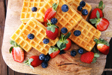 Board of belgian waffles with fresh berries on wooden background