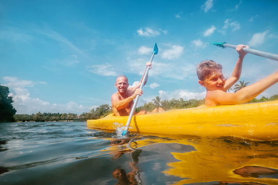 Father and son are sailing in the canoe in tropical lagoon