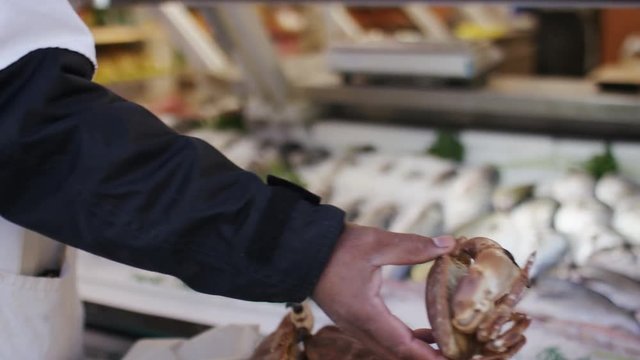 Male hand puts a live crab back onto display at a fishmonger shop