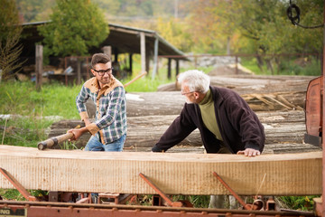 Fototapeta premium Father and son cutting wood log