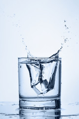 Ice cube is dropping in to the glass of pure water.