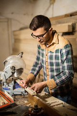 Young carpenter in his shop with a table saw