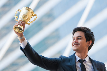 Success business man holding golden trophy cup with right hand, Business executives rejoice in...
