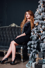 Fototapeta na wymiar A young girl in a beautiful dress near spruce Christmas decor.