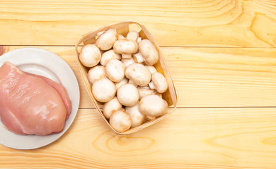 raw chicken fillet and mushrooms on a wooden background. place for text