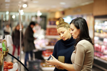 Two women choosing a dairy products at supermarket
