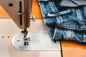 From the tailor: sewing machine about to adjust a pair of blue jeans.