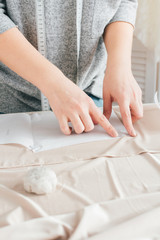 Obraz na płótnie Canvas Young seamstress makes clothes cutting fabric