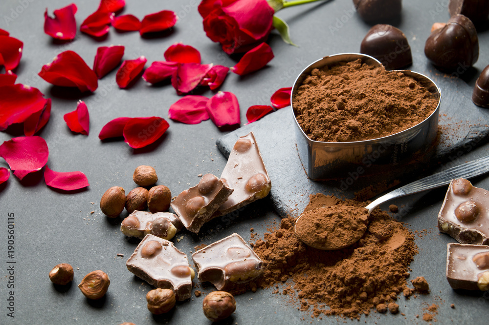 Wall mural Pieces of chocolate and cocoa on a black stone background