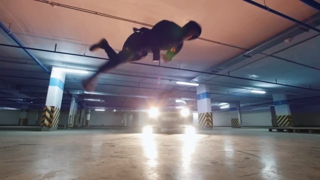 Young acrobat man athlet performs tricks at underground parking