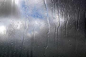 Rain drops on glass with dark clouds. Weather forecast.