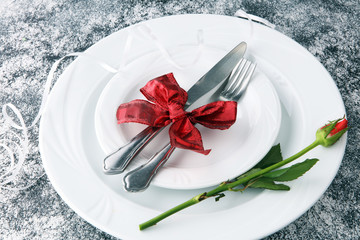 Festive table setting for Valentine's Day with fork, knife and rose