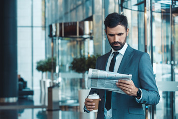 Businessman in a fromal suit in a business center morning newspaper and coffee