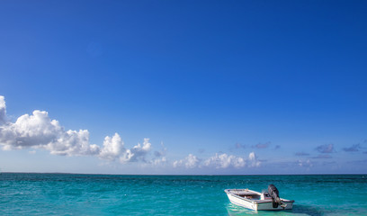 A small motorized rescue boat docked by an expansive ocean view under blue cloudy sky