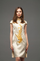 Portrait of a slender beautiful girl in an Asian elegant dress with a dragon print