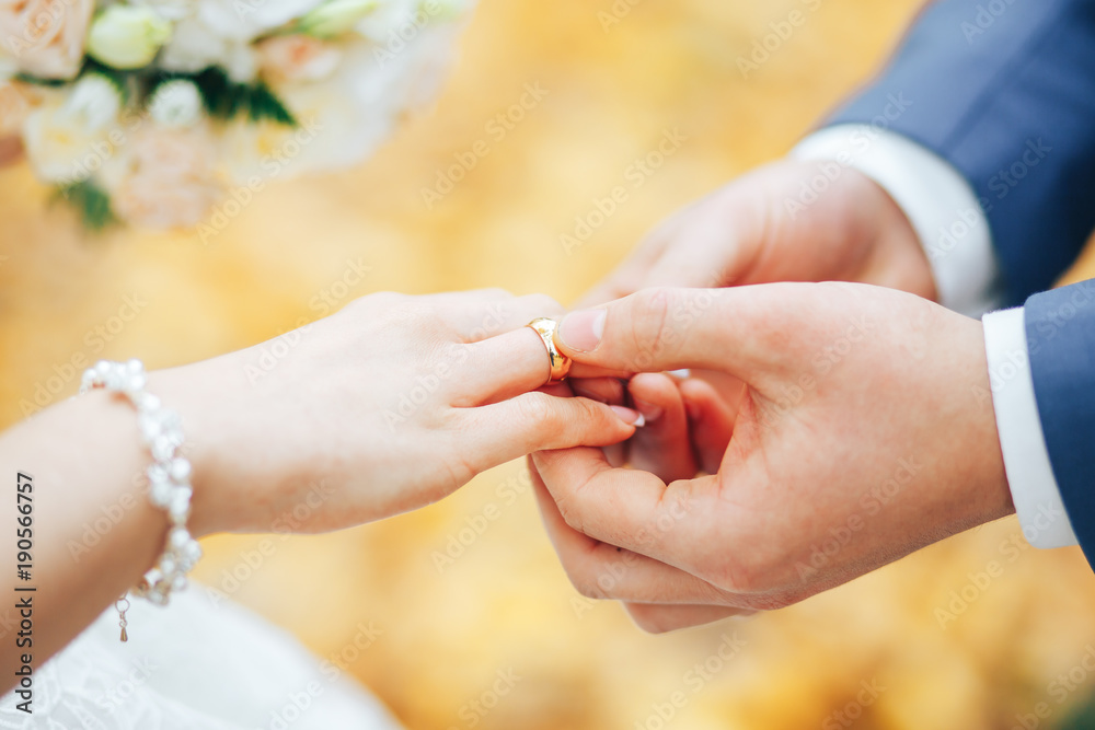 Wall mural the groom wears a gold ring to the bride at the wedding ceremony. wedding in autumn