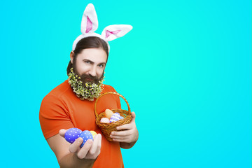 Happy Easter concept. Nice kind muscle man male with flower's beard, white ears of rabbit and...