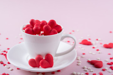 Valentine's Day background . Many little colorful sprinkles hearts in a cup. Creative concept.