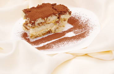 Cake tiramisu with an image of a fork on a plate sprinkled with chocolate